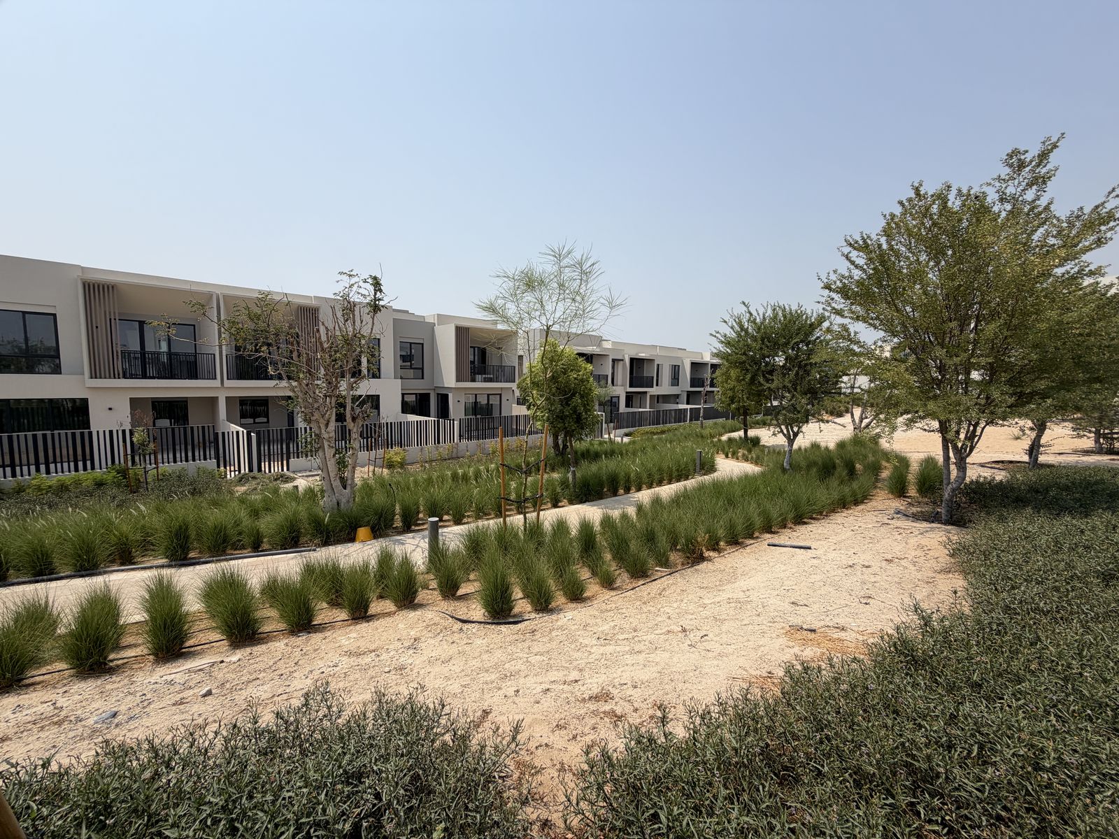 Green walking trail alongside townhouses in Jebel Ali Village, photographed September 2026